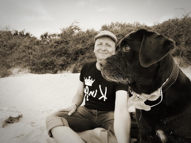 Photo un jeune homme avec un chien assis sur la terre ferme