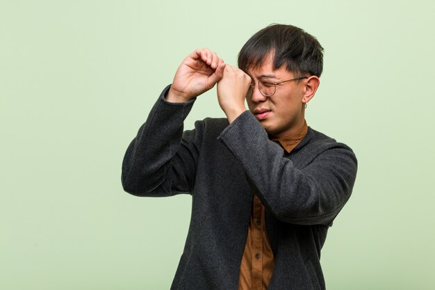 Jeune homme chinois contre un mur vert