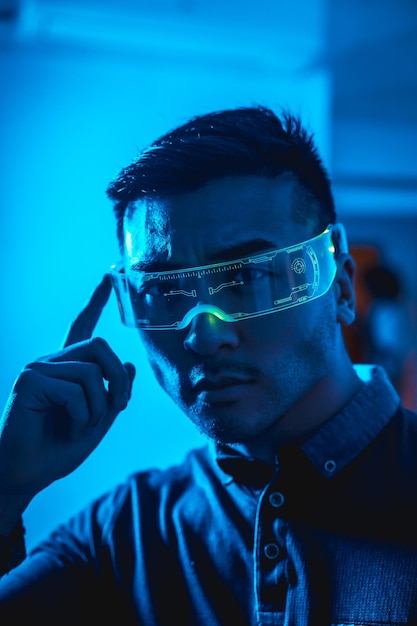 Jeune homme chinois avec des lunettes au néon avec un concept futuriste de lumière bleue cyber technologie humaine