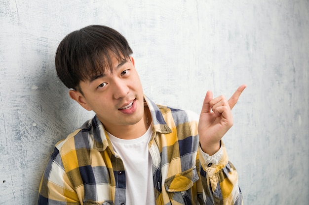 Jeune homme chinois visage agrandi pointant sur le côté avec le doigt
