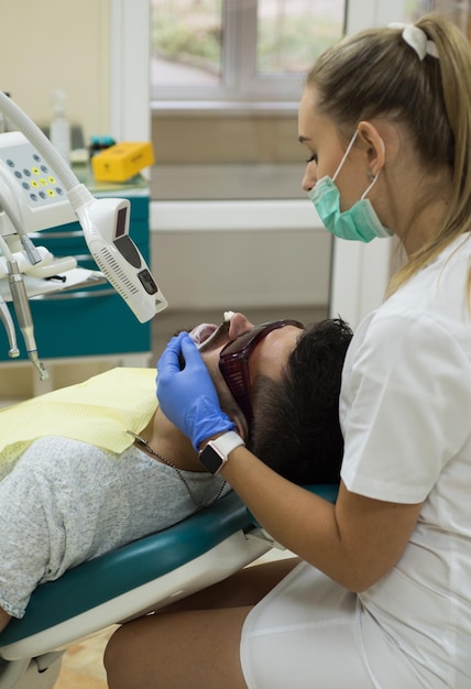 Jeune homme choisissant la couleur des dents chez le dentiste en gros plan Homme barbu faisant examiner les dents chez le dentiste Homme senior ayant un traitement dentaire au cabinet du dentiste