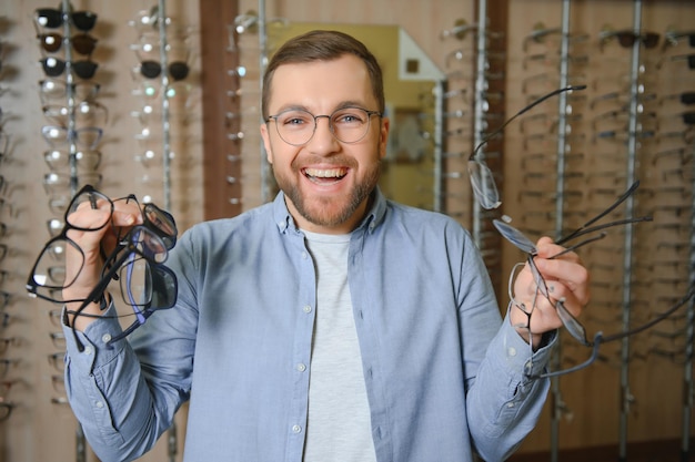 Jeune homme choisissant des lunettes au magasin d'optique