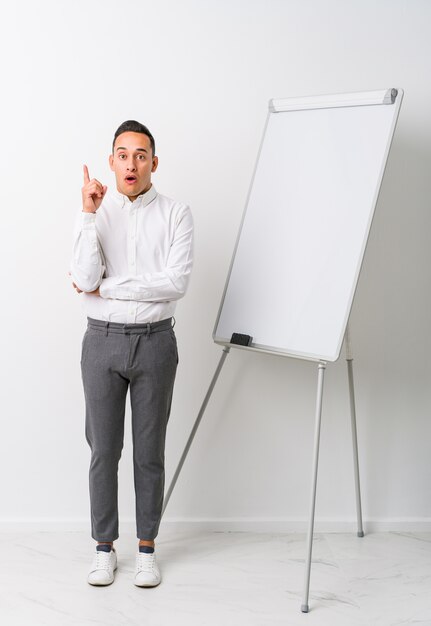 Jeune homme de coaching latin avec un tableau blanc isolé ayant une excellente idée, concept de créativité.