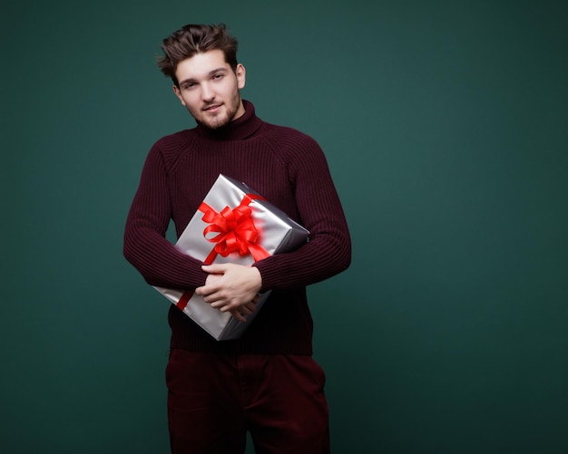 Jeune homme, coffrets cadeaux arcs de soie rouge Nouvel An Noël Photo de mode Studio Shot Fond vert