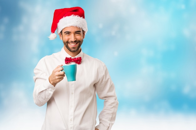 Jeune homme coiffé d&#39;un chapeau de père Noël le jour de Noël