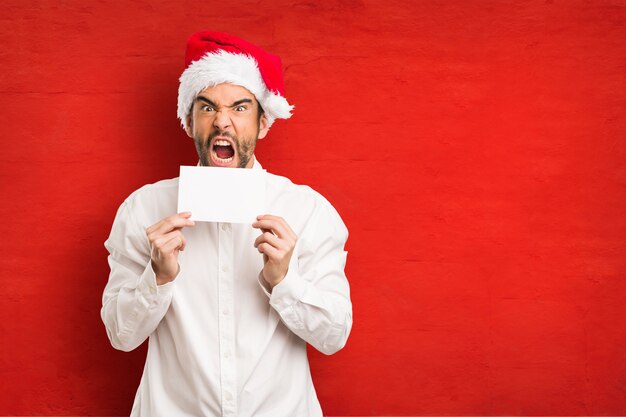 Jeune homme coiffé d&#39;un chapeau de père Noël le jour de Noël