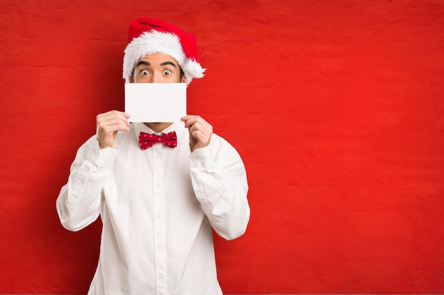 Jeune homme coiffé d&#39;un chapeau de père Noël le jour de Noël