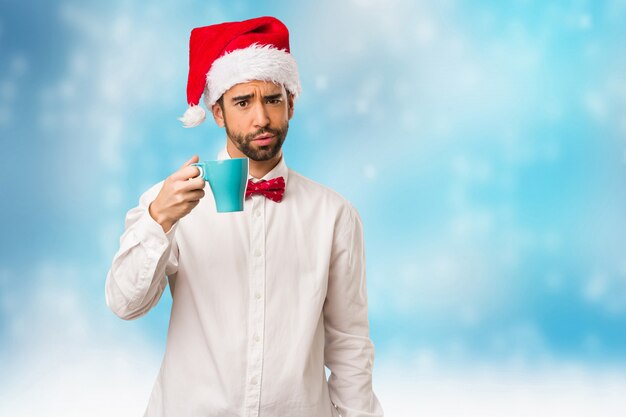 Jeune homme coiffé d&#39;un chapeau de père Noël le jour de Noël