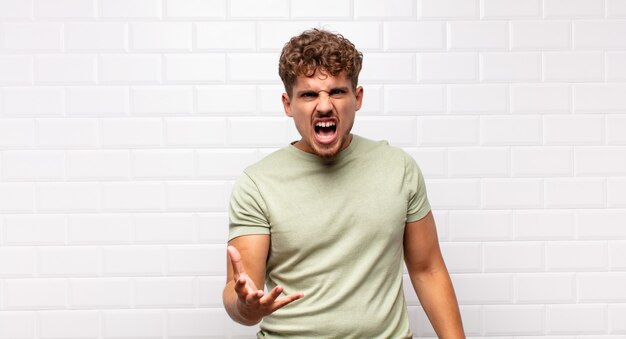 Jeune homme à la colère, agacé et frustré hurlant wtf ou qu'est-ce qui ne va pas avec vous