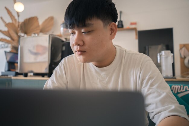 Jeune homme concentré portant un masque médical à l'aide d'un ordinateur portable en tapant sur le clavier en écrivant un e-mail