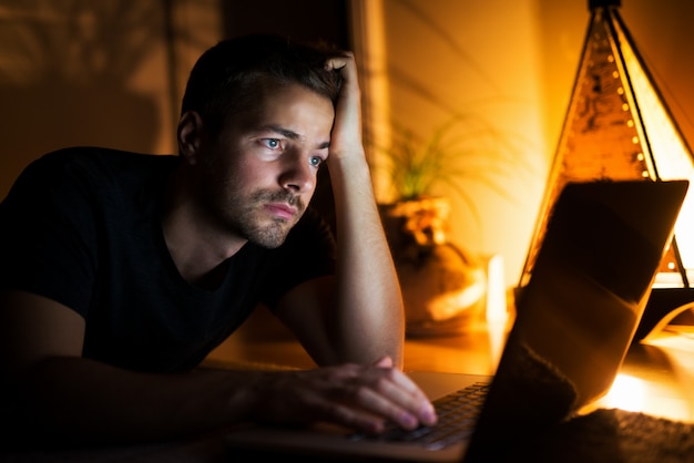 Jeune homme concentré à la recherche d'informations sur internet, à la fatigue