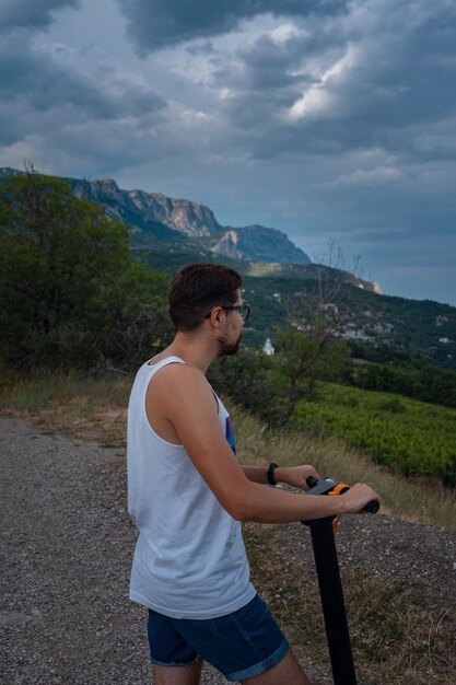 Jeune homme conduisant un scooter électrique sur la chaîne de montagnes Concept de transport écologique