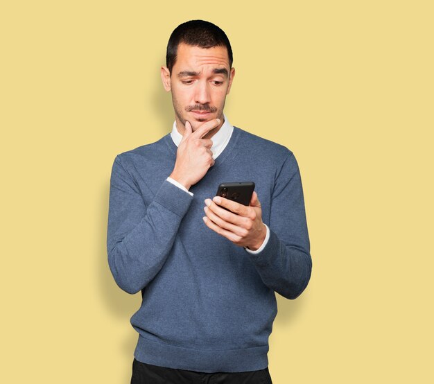 Jeune homme confus à l'aide d'un téléphone mobile