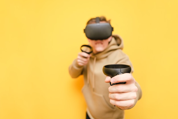 Jeune homme avec contrôleur dans ses mains et casque VR jouant à des jeux vidéo