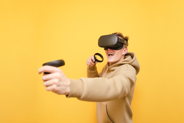 Jeune homme avec contrôleur dans ses mains et casque VR jouant à des jeux vidéo