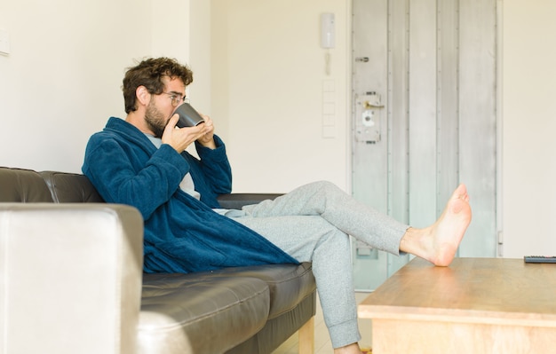 Jeune homme cool assis sur un canapé au salon devant la télé