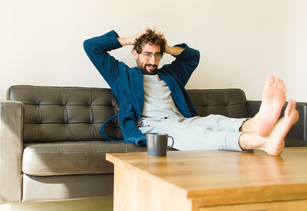 Jeune homme cool assis sur un canapé au salon devant la télé