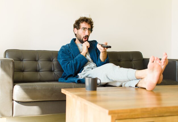 Photo jeune homme cool assis sur un canapé au salon devant la télé