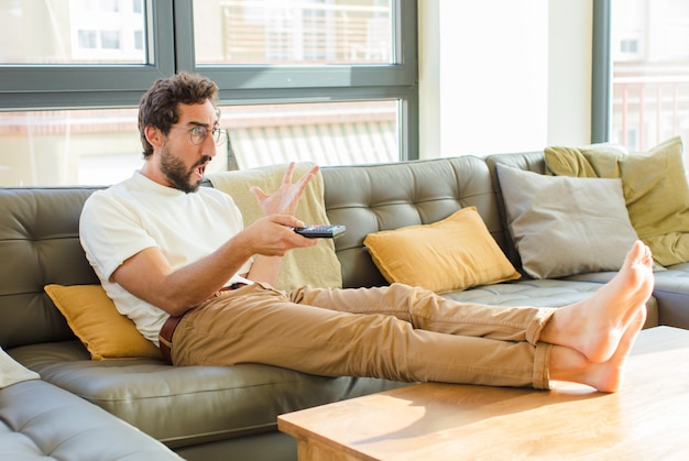 Jeune homme cool barbu assis sur un canapé à la maison