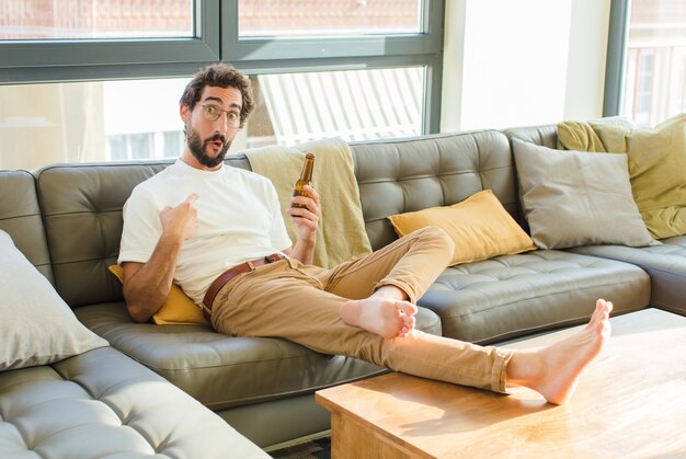 Jeune homme cool barbu assis sur un canapé à la maison