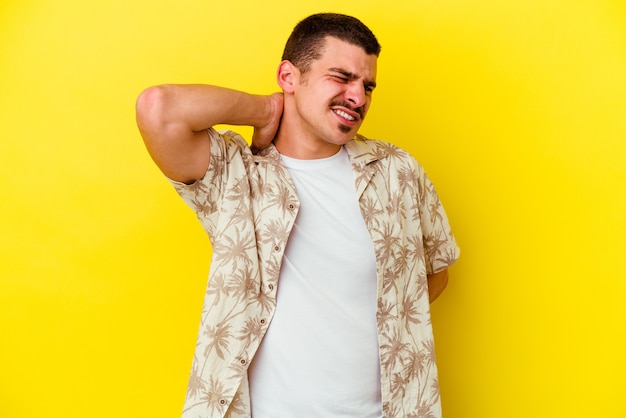 Jeune homme cool caucasien isolé sur fond jaune fatigué et très endormi en gardant la main sur la tête.