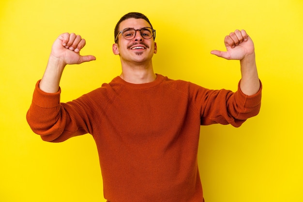 Jeune homme cool caucasien sur jaune se sent fier et sûr de lui, exemple à suivre.