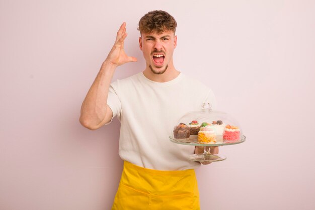 Jeune homme cool criant avec les mains en l'air concept de gâteaux faits maison