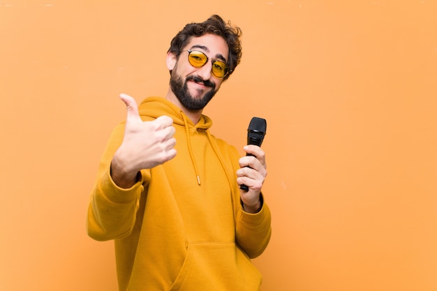 Jeune homme cool fou avec un microphone sur le mur orange