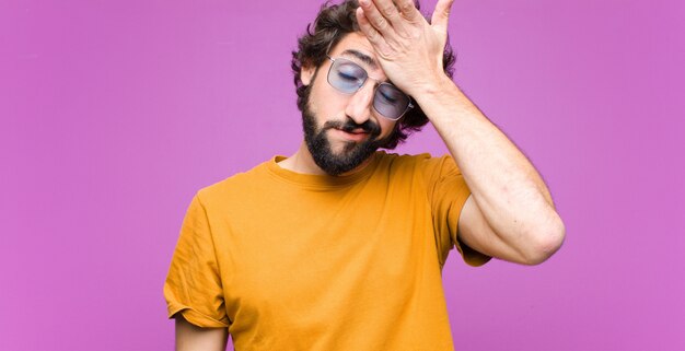 Jeune homme cool fou à la recherche de stress, fatigué et frustré, sécher la sueur sur le front, se sentir désespéré et épuisé contre le mur plat