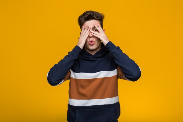 Jeune homme cool portant un sweat à capuche cligner des yeux effrayé et nerveux.