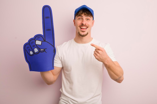 Jeune homme cool qui a l'air excité et surpris en montrant le concept de ventilateur numéro un