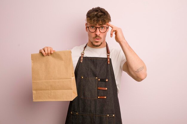 Jeune homme cool qui a l'air surpris de réaliser une nouvelle idée de pensée ou un livreur de concept et de la restauration rapide