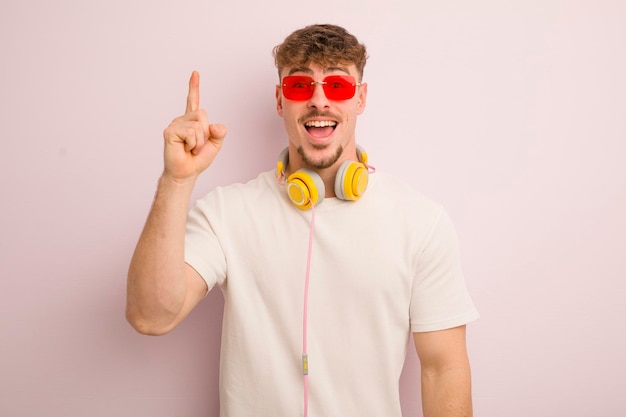 Jeune homme cool se sentant comme un génie heureux et excité après avoir réalisé une idée de lunettes de soleil et d'écouteurs