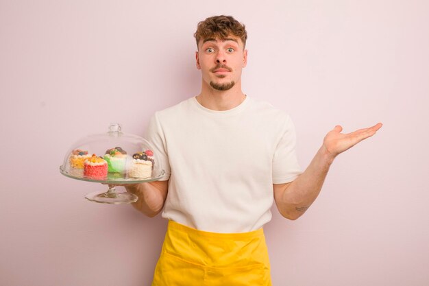 Jeune homme cool se sentant perplexe et confus et doutant du concept de gâteaux faits maison