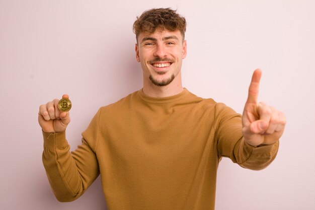 Jeune homme cool souriant et sympathique montrant le concept de bitcoin numéro un