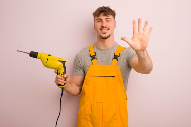 Jeune homme cool souriant et sympathique montrant le concept de bricoleur et de perceuse numéro cinq