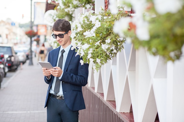 Jeune homme en costume d'affaires tenant une tablette le jour de l'été