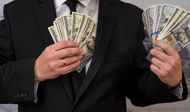 Jeune homme en costume mettant des billets d'un dollar dans sa poche Concept de pots-de-vin ou de corruption