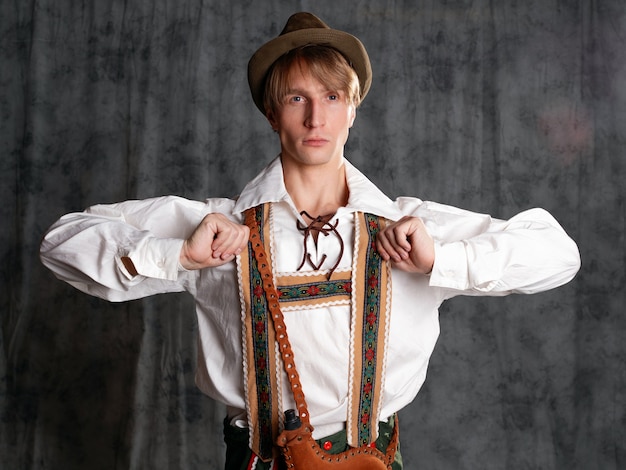 Un jeune homme en costume national bavarois avec un short à bretelles et un chapeau