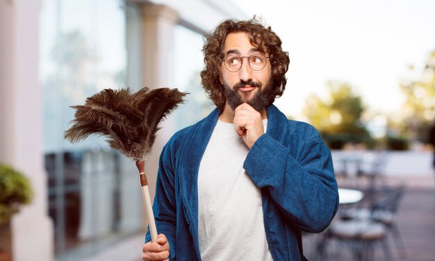 Jeune homme en costume de nuit en peignoir avec un plumeau