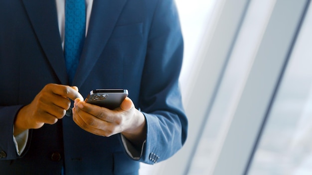 Jeune homme en costume utilisant un smartphone au bureau