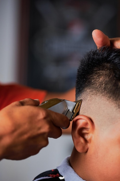 Jeune homme coupant les cheveux d'un garçon dans un salon de coiffure