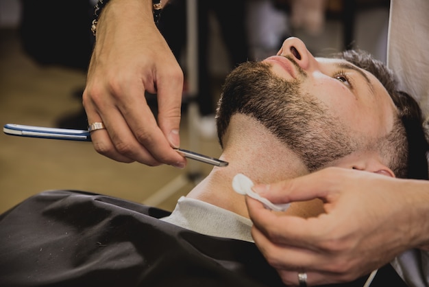 Jeune homme avec coupe de cheveux tendance au salon de coiffure.