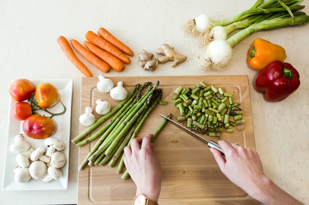 Jeune homme coupe des légumes frais dans la cuisine.