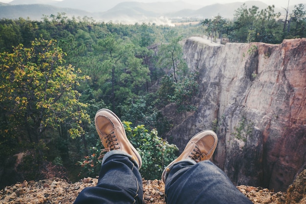 Jeune homme courageux assis sur un haut Grand Canyon