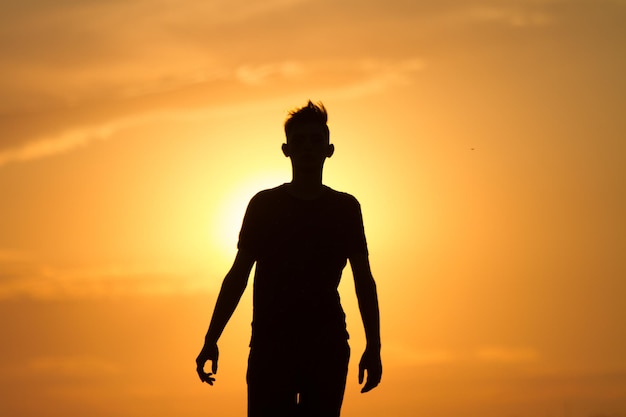 jeune homme courant et montrant le mouvement au coucher du soleil