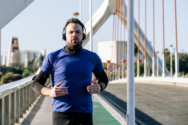 Jeune homme courir et écouter de la musique dans une zone urbaine