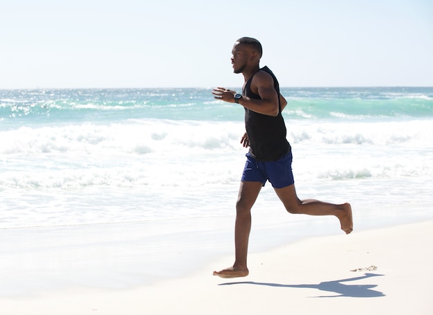 Jeune homme courir pieds nus à la plage