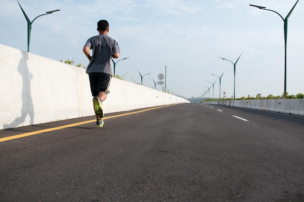 Jeune homme courir sprinter sur la route