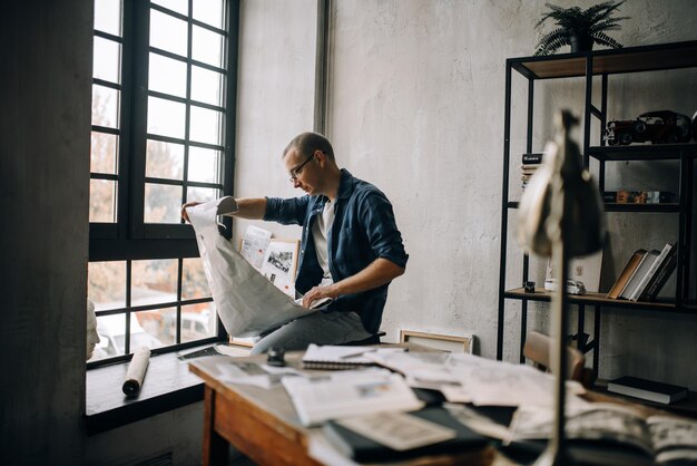 Photo un jeune homme créatif examine un livre whatman déplié dans son atelier dans le contexte d'al